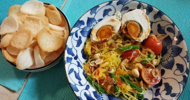 Một đĩa gỏi đu đủ xanh cay nồng với tôm khô, đậu phộng, cà chua bi, đậu đũa và nước sốt trộn đậm đà.